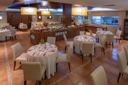 a restaurant with white tables and chairs and a buffet at Serhs Natal Grand Hotel & Resort in Natal