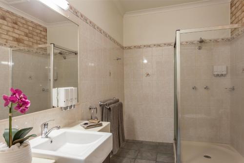
a bathroom with a shower, sink, and mirror at Highlander Motor Inn in Toowoomba
