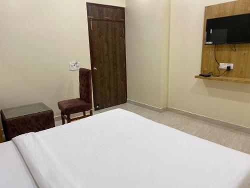 ein Schlafzimmer mit einem Bett, einer Tür und einem Stuhl in der Unterkunft Hotel ashiyana stay in Lucknow
