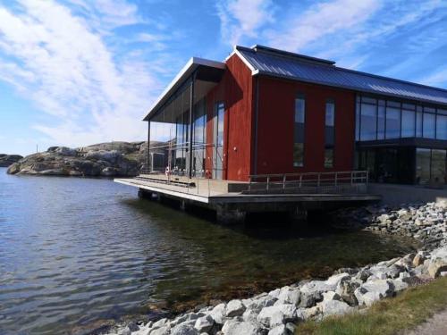 a red building on a dock next to the water at A nice little cottage in Henån in Henån