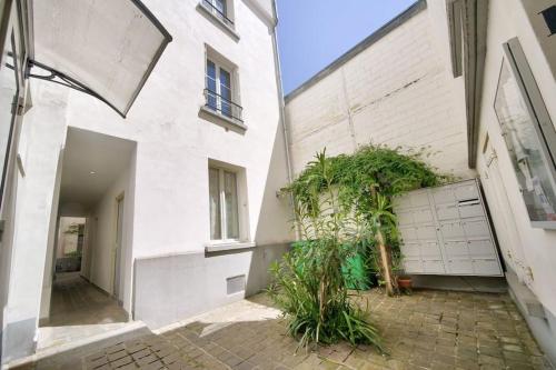 un grand bâtiment blanc avec une cour ornée de plantes dans l'établissement Studio sur cour, proche des Buttes-Chaumont, à Paris