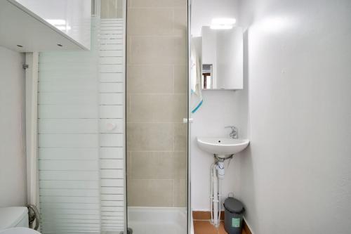 une salle de bain blanche avec un lavabo et une douche dans l'établissement Studio sur cour, proche des Buttes-Chaumont, à Paris