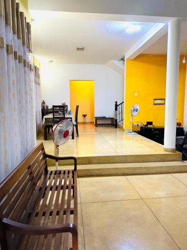 a living room with a bench and a yellow wall at THE NIGHT SHADE B01 in Negombo