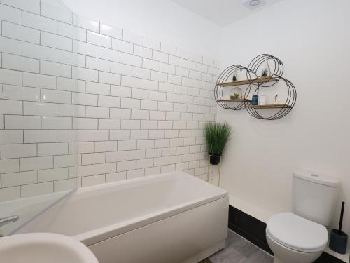 a white bathroom with a tub and a toilet at Stunning 2 Bed Apartment in Converted Church in Blackpool