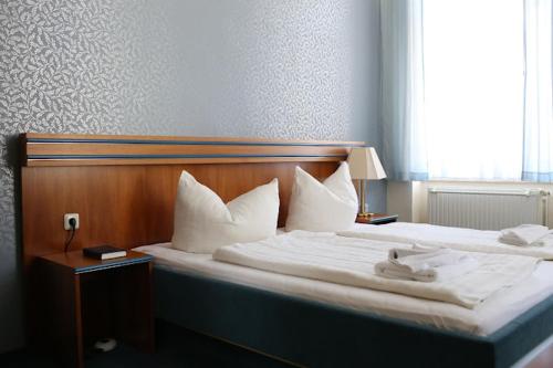 a bedroom with a large bed with white sheets and pillows at Rathaushotel in Eibenstock