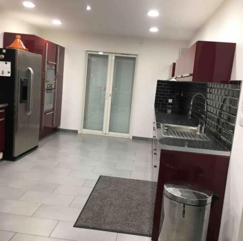a kitchen with red cabinets and a stainless steel refrigerator at Villa charmante avec piscine à Saint-Gilles in Saint-Gilles
