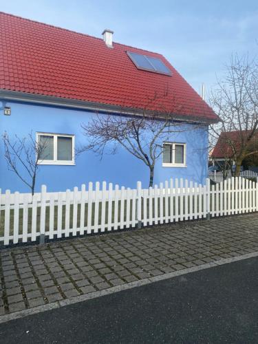a blue house with a white fence and a red roof at Ferienwohnung Patrick in Amberg