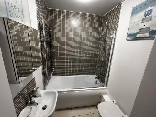 ein Badezimmer mit einer Badewanne, einem Waschbecken und einem WC in der Unterkunft Palmer House Apartment in Ryde