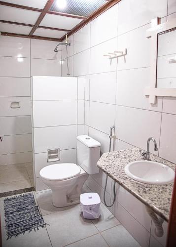a white bathroom with a toilet and a sink at Pousada das Gaivotas in Guaibim
