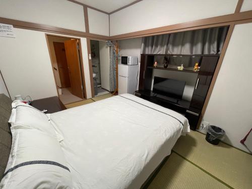 a small bedroom with a white bed and a television at 福宿 Fukuinn 202号室 in Takamatsu