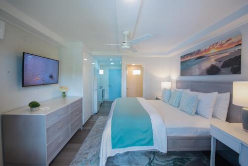 a white bedroom with a large bed and a desk at Blue Haven Holiday Apartments in Christ Church