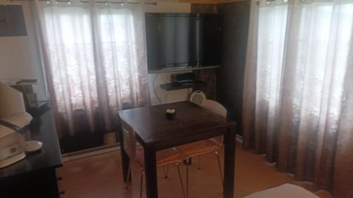 a room with a table and a television and curtains at Maison trois chambres in Schwändi