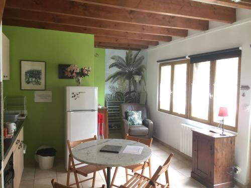 eine Küche mit einem Tisch und Stühlen sowie einem Kühlschrank in der Unterkunft La maisonnette in Les Andelys