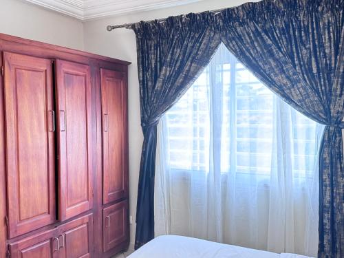 a bedroom with a bed and a window with curtains at Akhard Haus in Buea