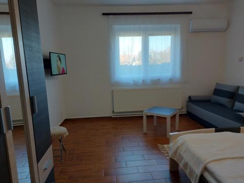 a living room with a blue couch and a bed at Potyka Apartman in Tiszafüred