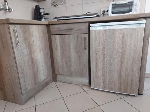a kitchen with wooden cabinets and a dishwasher at Potyka Apartman in Tiszafüred