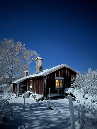 una cabaña con nieve en el suelo frente a ella en Heritage-listed country cottages en Eskilstuna