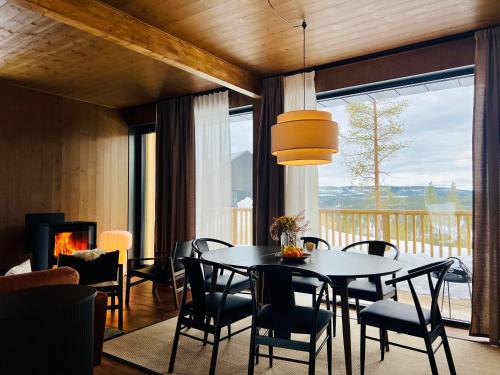 ein Esszimmer mit einem Tisch, Stühlen und einem Kamin in der Unterkunft The Riverside Mountain Lodge - 110sqm of Calm Luxury in Idre