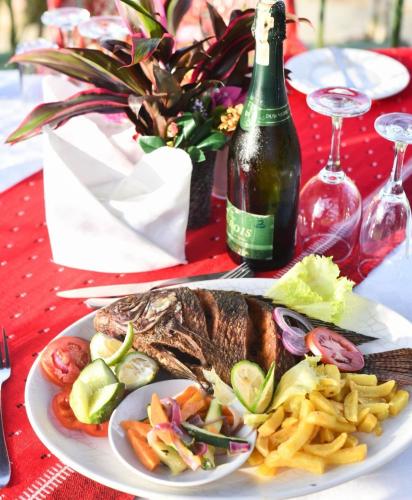 a plate of food on a table with a bottle of wine at Country Lake Resort Garuga in Wakiso