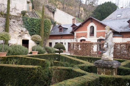 un giardino con una statua di fronte a una casa di Manoir des Basses Rivières a Rochecorbon