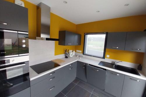 d'une cuisine avec des placards gris et des murs jaunes, ainsi que d'une fenêtre. dans l'établissement Beautiful new modern house, à Baden