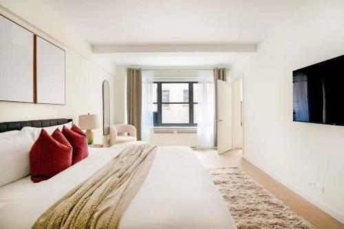 a white bedroom with a large bed with red pillows at 52-3DE Newly renovated 2BR BTH Midtown East in New York