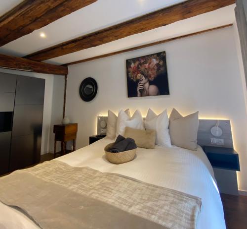 Un dormitorio con una cama blanca con una cesta. en Gîte Du XVe en Kaysersberg