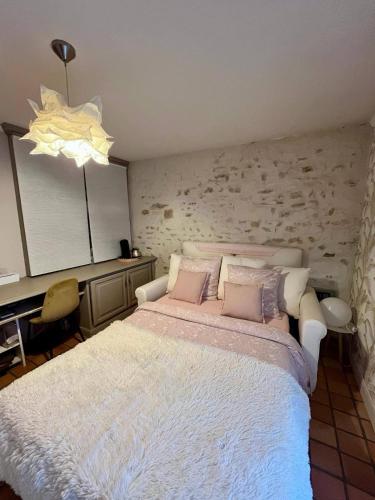 1 dormitorio con 1 cama blanca grande con almohadas rosas en Suite dans longère, 