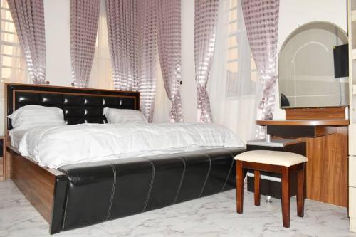 a bedroom with a black bed and a stool and a mirror at FAMVILLE in Ikota