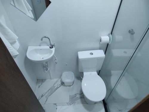 a white bathroom with a toilet and a sink at LONDRES HOTEL in Gama