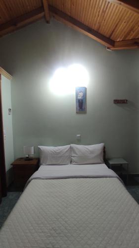 a bedroom with a large white bed with a light on the wall at AGNANTIO in Monemvasia