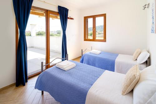 トルトリにあるAttico Luxuryの青いカーテンとバルコニーが備わる客室で、ベッド2台が備わります。