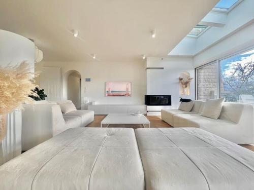 un salon avec des meubles blancs et une grande fenêtre dans l'établissement Villa contemporaine d'architecte, à Bonneville