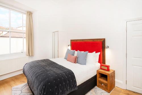 a bedroom with a large bed with a red headboard at Berkeley Suites in Bristol