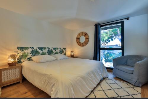 une chambre avec un lit, une chaise et une fenêtre dans l'établissement Luxueuse villa avec piscine et vue panoramique - Villa Perry, à Saint-Cyr-sur-Mer