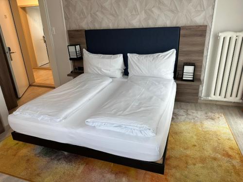 a large bed with white sheets and pillows at Hotel Spatz in Luzern