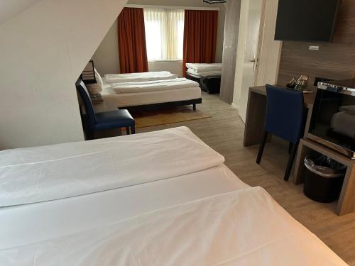 a room with three beds and a table and a kitchen at Hotel Spatz in Luzern