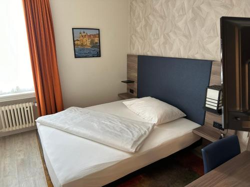 Schlafzimmer mit einem weißen Bett und einem TV in der Unterkunft Hotel Spatz in Luzern
