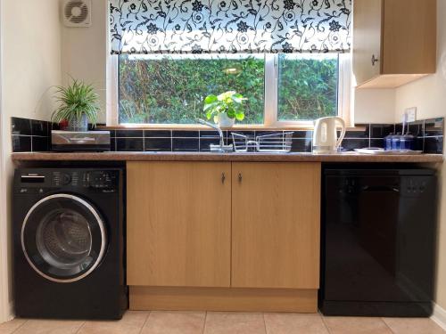 eine Küche mit einer Waschmaschine und einem Fenster in der Unterkunft Squirrels Nest - Pet Friendly in Rookley