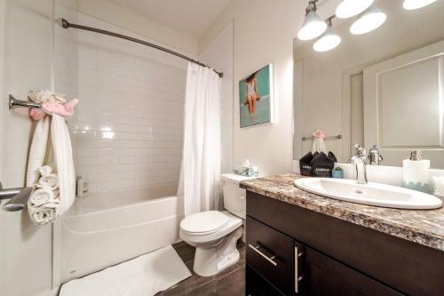 埃德蒙頓的住宿－Beach Vibes - KING Bed - Fireplace - Garage - WiFi，浴室配有盥洗盆、卫生间和浴缸。
