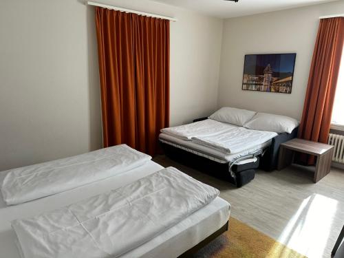 a room with two beds and an orange curtain at Hotel Spatz in Luzern