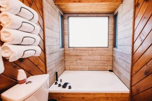 een kleine badkamer met een bad en een raam bij Cozy Cabin in Pocono Farms with Hot tub Fire pit and close to many attractions in Pocono Country Place