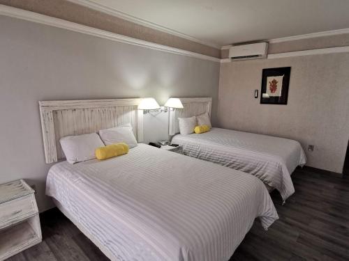 Cette chambre comprend 2 lits avec des draps blancs et des oreillers jaunes. dans l'établissement Paraíso Express, à Torreón