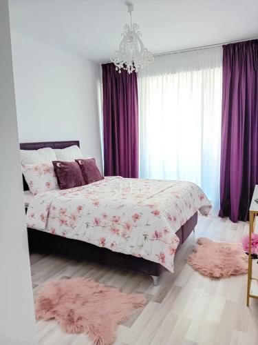 a bedroom with a bed with purple curtains and pink rugs at Safirului apartment in Bragadiru