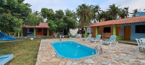 a swimming pool in a yard next to a house at Pousada Portal dos Coqueirais in Jequia da Praia