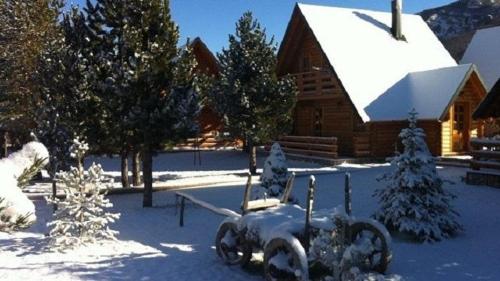 a snow covered yard with a tractor in front of a cabin at Blidinjehouse in Risovac