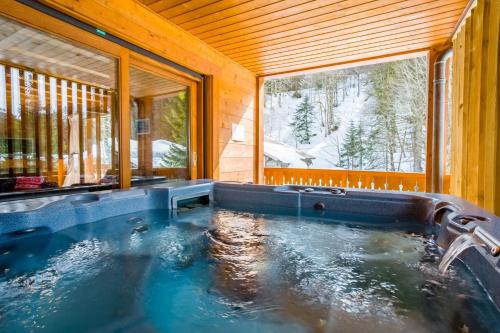 a hot tub in a wooden house with a window at Chalet Les Grolets - Ardent in Montriond