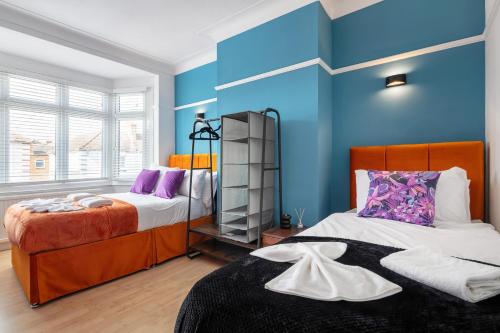a bedroom with two beds and a blue wall at Welcome to Northview House Stylish 4 Bedroom Home in Southend by Jesswood Properties Contractors Corporates Relocation Stays Long Stays Welcome in Southend-on-Sea