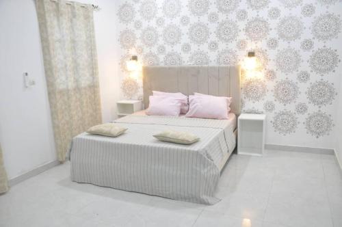 a bedroom with a bed with pink pillows and a wall at Apparemment chic et lumineux in Dassasgo