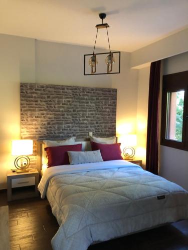 a bedroom with a large bed with a brick wall at Villa Under Meteora in Kalabaka